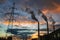 Silhouette of steel lattice tower, chimneys smoke on sunset sky background. Transmission tower and industry pipes