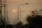 Silhouette of street with light poles, high voltage electricity posts and cables along the way