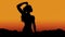 Silhouette of strong and empowered woman on orange sunset sky