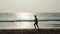 Silhouette student tourist young athlete runner man with fit strong body training on beautiful Summer sunset beach sand