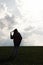 silhouette of stylish beautiful brunette girl in the windy evening outdoors in spring field, lonely standing