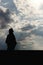 silhouette of stylish beautiful brunette girl in the windy evening outdoors in spring field, lonely standing