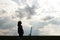 silhouette of stylish beautiful brunette girl in the windy evening outdoors in spring field, lonely standing