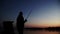 Silhouette successful fisherman catching fish and spinning fishing reel