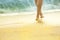 silhouette of sunburnt legs of woman walking along sea beach lit by sun.