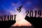Silhouette sunset background. A man is jumping over to cliff and jump across between start! and 2019 word.