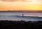 Silhouette of Surfer Riding a Wave at Sunset whit Seascape and Mountain as Background