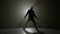 Silhouette of a talented young dancer dancing hip hop street dance on a stage in front of the spotlight -
