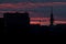 A silhouette of a tall telecommunication broadcasting tower against the vivid red sky on a cloudy summer evening