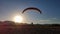Silhouette of tandem paragliders land