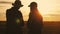 Silhouette team farmers stand in a wheat field with tablet at sunset. Partnership concept.