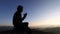 Silhouette of teenage boy praying to God on  autumn sunrise background, religious concept