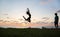 silhouette of teenager girl joyfully bounces, has fun at sunset by sea