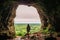 Silhouette of a teenager girl standing by a cave entrance, beautiful nature in the background. Travel, holiday and adventure