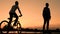 Silhouette of teenagers at sunrise. One boy rides on a self-balancing two-wheeled gyroscope and another young man on a