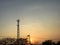 Silhouette of telecommunication tower, electrical power lines and tree branches during sunset