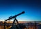 Silhouette of a telescope aimed at the stars of the galaxy on the background of the night city. Image on the topic of research,