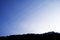 Silhouette of a thick forest and powerlines under a clear blue sky background