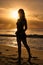 Silhouette of a thin woman at sunset by the sea. A full-length girl stands on the shore of the ocean at dawn. Vacation