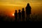 Silhouette of three children and mom standing at mountain. There is a sunset in the background,a
