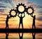Silhouette of the three men holding the gears put them together in one gear