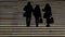 Silhouette of three people coming down a staircase light