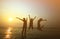 Silhouette of three young girls jumping with hands up