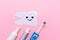 A silhouette of a tooth carved out of felt with a smiling cartoon face, next to an electric toothbrush, mouth freshener and
