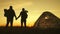 Silhouette tourist couple standing holding hands and watching the sunset near tent in vacation. Camp rest lifestyle