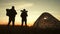Silhouette tourist couple standing holding hands and watching the sunset near tent in vacation. Camp rest lifestyle