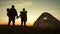 Silhouette tourist couple standing holding hands and watching the sunset near tent in vacation. Camp rest lifestyle