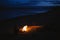 Silhouette of tourist girl around campfire at night on the river shore.