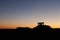 A silhouette of a tractor harvesting potatoes at night