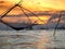 Silhouette of traditional fishing method using a bamboo square dip net with sunrise sky background