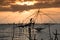 Silhouette of traditional fishing method using a bamboo square dip net with sunrise sky background