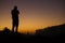 Silhouette of a travel photographer watching and taking photos of  the dramatic sunrise in the valley with orange and purple sky.