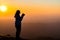 Silhouette of traveler female with camera smart phone and taking photo enjoying in the mountains at Khao Chang Puak mountain