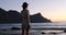 silhouette of traveler girl in safari clothes on the ocean, enjoying the sunset