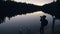 Silhouette traveler photographing scenic view in forest, river. Wood pier. One woman shooting nice dark magic night look