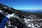 Silhouette of traveler stands in distance on dark slope of Villarrica volcano covered with fresh snow