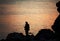 Silhouette of trekker on rocky seashore near camping tent on overnight stay