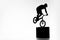 silhouette of trial cyclist performing stunt while balancing on cube
