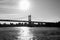 Silhouette of Triborough bridge over reflective river and buildings in black and white style