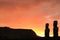 Silhouette of two of 15 huge Moai statues at Ahu Tongariki against orange color sunrise sky, Easter Island, Chile