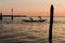 Silhouette of two athletes rowing on a flat boat against the background of evening Venice, Italy.