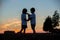 Silhouette of two children, boy brothers, making heart shape wit