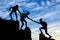 Silhouette of two climbers in the mountains help another climber