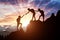 Silhouette of two female mountaineers helping another female mountaineer to overcome the obstacle in the mountains