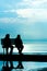 Silhouette of two friends sitting on wood bench near beach