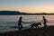 Silhouette of Two Kids Playing With Dog on Lake Shore